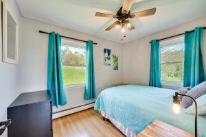 una camera da letto con tende blu, un letto e un ventilatore di 8 Mi to Jay Peak Resort Scenic Retreat with Deck a North Troy