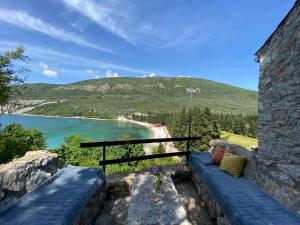 a blue couch sitting on a stone wall overlooking a beach at Stone & Sea house in Valdanos