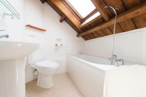 a bathroom with a toilet and a tub and a sink at Tanglewood Cottage - Lancombes House in Powerstock +13 photos
