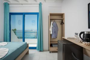 a bedroom with a bed and a window with a view of the ocean at Finikas Resort Sfakia - Seaside Rooms in Loutro
