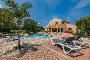 a villa with a swimming pool and a house at Sunny Paradise Villa in Noord