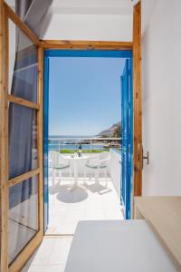 an open door to a balcony with a table and chairs at Finikas Resort Sfakia - Seaside Rooms in Loutro