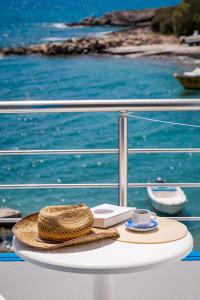a straw hat and a book on a table on a boat at Finikas Resort Sfakia - Seaside Rooms in Loutro