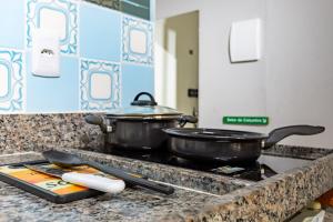 two pots and pans sitting on top of a stove at Estúdio aconchegante e funcional - cama casal ou 2 de solteiro - ar condicionado - wifi - netflix - cozinha in Brasilia +28 photos