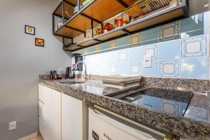 a kitchen with granite counter tops and blue and white tiles at Estúdio aconchegante e funcional - cama casal ou 2 de solteiro - ar condicionado - wifi - netflix - cozinha in Brasilia