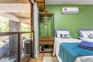 two beds in a room with a green wall at Estúdio aconchegante e funcional - cama casal ou 2 de solteiro - ar condicionado - wifi - netflix - cozinha in Brasilia
