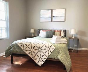 a bedroom with a bed with a blanket and two lamps at Orange Crush Cottage- Downtown Beaches & Dining in Wilmington