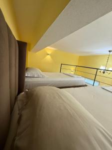 two beds in a room with yellow walls at Auto Tana Guest House in Tirana