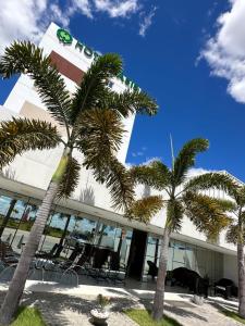 a hotel with palm trees in front of a building at Hotel Oásis de Patos in Patos