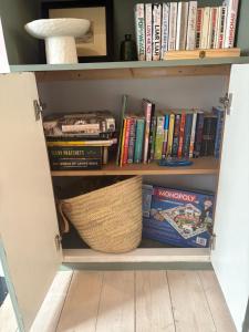 a book shelf with books and a basket on it at Hurrell Cottage in Cambridge
