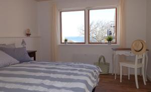 a bedroom with a bed and a desk and a window at Badepensionat Sandloppen in Sandvig