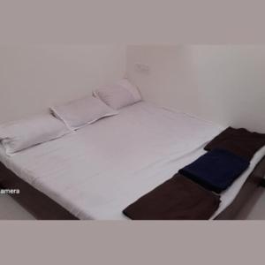 a bed with white sheets and a blue blanket at Ashish Aram Ghar in Ujjain