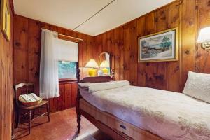 Schlafzimmer mit Holzwänden, einem Bett und einem Fenster in der Unterkunft Rustic Rockport Cottage in Rockport