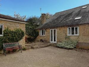a brick house with a bench in front of it at Tanglewood Cottage - Lancombes House in Powerstock