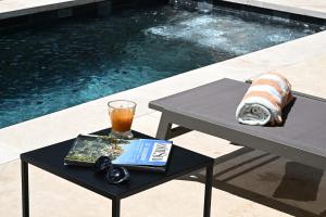 a table with a book and a drink on it next to a pool at Le Mazet de la Truffière in Gordes