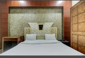 a bedroom with a large white bed and a desk at Hotel New Royal Plaza in Chandīgarh