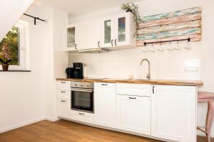 a white kitchen with white cabinets and a sink at Ferienwohnung Kunterbunt Eckernförde in Eckernförde +13 photos