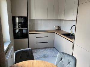 a kitchen with white cabinets and a table and chairs at Apartament Parkowy in Augustów
