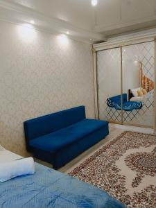 a living room with a blue couch and a bedroom at Уютная квартира ЖК Orynbor towers in Astana