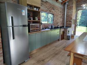 a kitchen with a refrigerator and a brick wall at Refúgio da Família Koch - casa de campo in Sinimbu