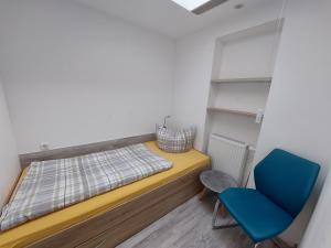 a small bedroom with a bed and a blue chair at Ferienquartier T5 Bahnhofstraße 6 in Trassenheide
