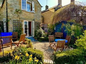 a garden with chairs and a table in front of a house at Lamorna Cottage in Chipping Norton