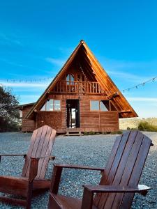 two chairs sitting in front of a log cabin at ThanSam Cabaña in San Vicente