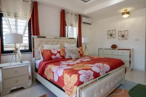 a bedroom with a large bed with a red comforter at Palms Rooftop Villa in Ocho Rios