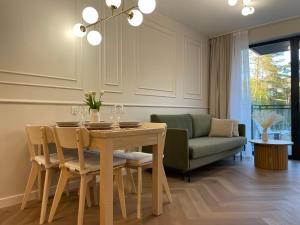 comedor con mesa y sofá verde en Apartamenty Premium Przy Plaży Morzlive, en Ustronie Morskie