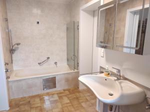 a white bathroom with a sink and a bath tub at Putz Appartements in Gröbming +6 photos
