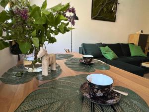 een houten tafel met twee kopjes en een vaas met bloemen bij Apartament Zimowa 16 in Srebrna Góra