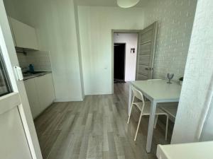 a white room with a table and a kitchen at ЖК Времена года Весна Кабанбай Батыра 46 in Taldykolʼ +3 photos
