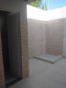 a bathroom with a door open on a brick wall at Casa aconchegante in Feira de Santana +3 photos