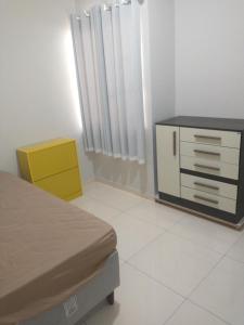 a bedroom with a bed and a yellow dresser at Casa aconchegante in Feira de Santana