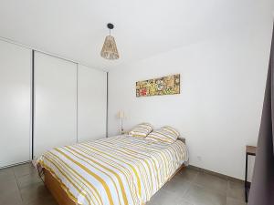 una camera da letto con un letto con una coperta a righe di Villa 6 couchages avec jardin a Ortaffa