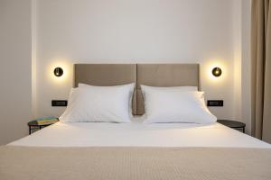 a bed with two white pillows and a headboard at Valianos Studios - Luxury Apartment in Alikanas