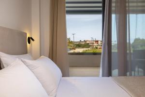 a bed with white pillows in front of a window at Valianos Studios - Luxury Apartment in Alikanas