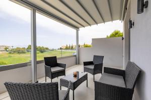 a balcony with chairs and a table and windows at Valianos Studios - Luxury Apartment in Alikanas