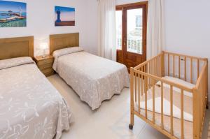 a bedroom with two beds and a crib at Apartamentos Sofía in Es Cana +46 photos