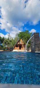 a swimming pool with a fountain in front of a house at Cabaña Alpina - Ecos del Cerro in Paraguarí