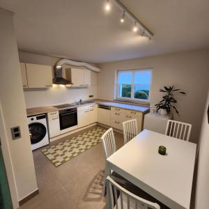 a kitchen with a white table and a table and chairs at Esmeralda Ferienwohnung mit Sonnenterrasse & großem Parkplatz in Ebersbach-Musbach