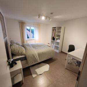 a bedroom with a bed and a desk and a window at Esmeralda Ferienwohnung Ebersbach-Musbach in Ebersbach-Musbach