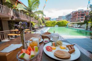 un tavolo con un piatto di prodotti per la colazione accanto a una piscina di Busy Bee Resort, Pokhara a Pokhara