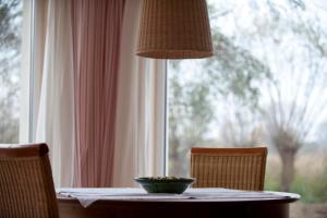 a table with a bowl of fruit on it next to a window at Ferienhausquartier Huberhof in Seehausen