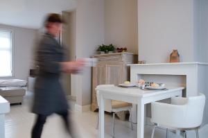 kobieta przechodząca przez salon z białym stołem w obiekcie De Pastorie - Zillebeke w mieście Ypres