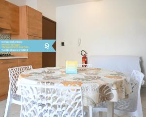 een eettafel met witte stoelen en een keuken bij RS317 - Marcelli, bilocale in residence fronte mare in Marcelli