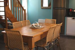 a wooden table with chairs and a kitchen with a staircase at COC - Bleu d'Opale in Wissant