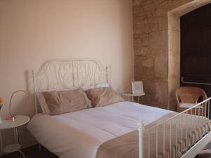 a white bed in a bedroom with two tables at Agriturismo Arà in Casale Zappulla