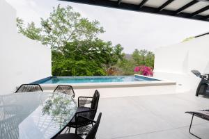 a patio with a table and chairs and a swimming pool at Casa Guapinol - con vista al Campo de Golf in Tangolunda