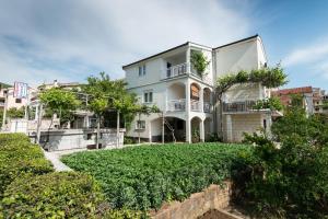 a large white house with a green yard at Apartments&Rooms SB in Neum
